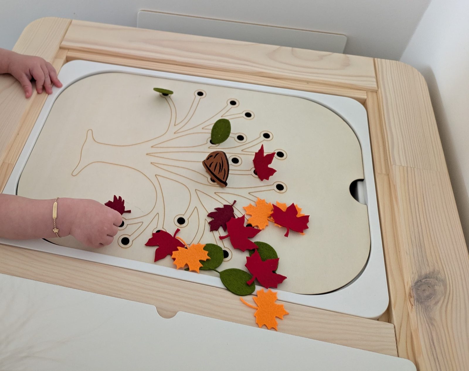 Een houten speeltafel met herfstbladeren en een tak