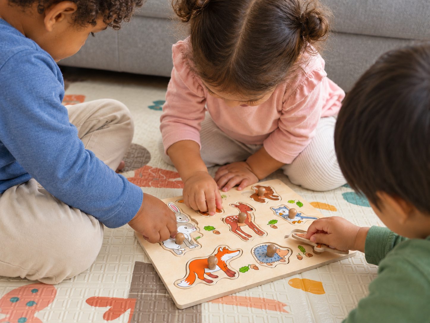 Drie kinderen puzzelen samen op een speelmat